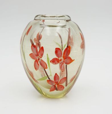 a glass vase with red flowers in it on a white surface