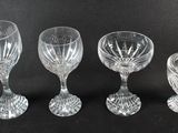 three glass goblets and a candle holder on a black surface