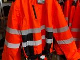 many orange jackets hanging on a rack in a store
