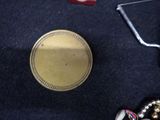 a gold medal sitting on a black carpet next to a pair of scissors