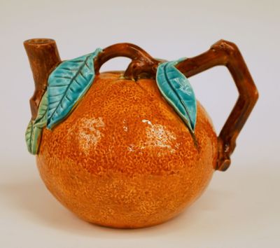 une théière en forme d'orange ornée d'une feuille verte