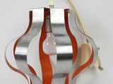 an orange and silver lamp hanging on a wall next to a white wall