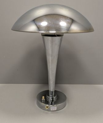une photo d'une lampe de table argentée posée sur une surface blanche
