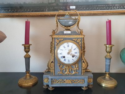 une horloge posée sur une table à côté de trois bougies