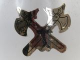 a silver and gold pin with two crossed axes on it