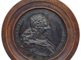 un vieux médaillon en bronze représentant un homme tenant un chien, sur fond blanc