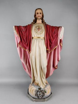 La statue de Jésus porte une robe rouge et tient une croix.