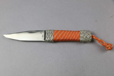 a small knife with an orange handle on a table