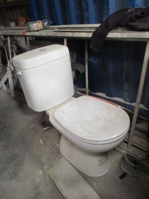 des toilettes blanches dans une pièce, avec un récipient bleu en arrière-plan