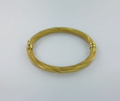 gros plan d'un bracelet en or sur une surface blanche