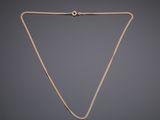 a gold necklace with a chain on a gray background