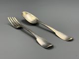 deux fourchettes et deux cuillères posées sur une table, sur fond gris