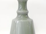 un vase vert avec une anse noire sur fond blanc