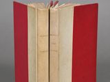 two red and white books sitting next to each other on a gray surface