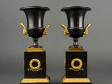 a pair of black and gold vases sitting on top of each other