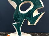 une sculpture verte et blanche posée sur une table en marbre