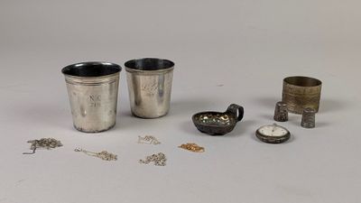 une coupe en argent et d'autres objets en argent posés sur une surface blanche