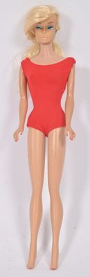une poupée Barbie en maillot de bain rouge, debout sur une surface blanche