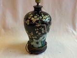 un vase noir et doré posé sur un socle, sur fond blanc
