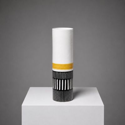 un vase blanc à rayures noires et jaunes, posé sur un socle blanc
