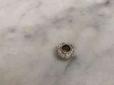a close up of a silver bead on a marble surface