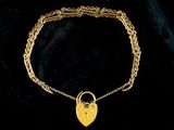 a gold bracelet with a heart shaped lock on it