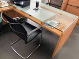 un bureau en verre sur lequel est posé un ordinateur, avec une chaise devant