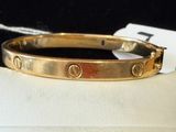 a close up of a gold bracelet on a white cloth