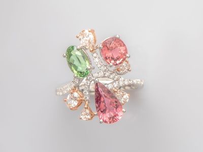 un gros plan sur une bague sertie de diamants roses, verts et blancs