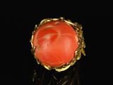 a close up of a gold ring with a coral stone in it