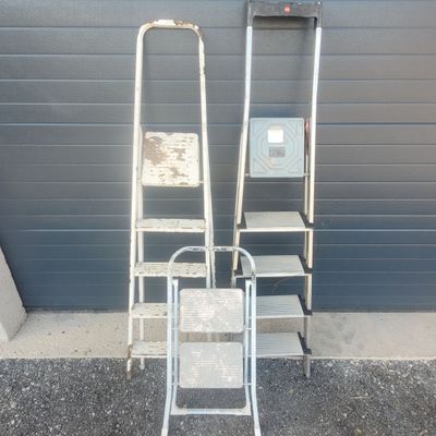two ladders and a chair in front of a building