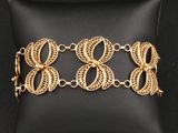 un bracelet plaqué or posé sur un coussin noir