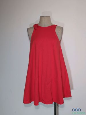 une robe rouge posée sur un mannequin contre un mur blanc