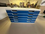 a close up of a blue and white chest of drawers on a table