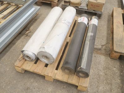 de nombreux rouleaux de tissu sur une palette dans un entrepôt