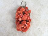 a small pendant made of coral beads on a white surface