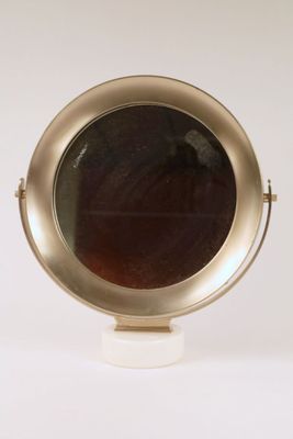 a small round mirror sitting on top of a white pedestal