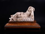 statue en marbre représentant une femme allongée sur un lit, sur fond noir