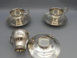 a set of three silverplated tea cups and saucers