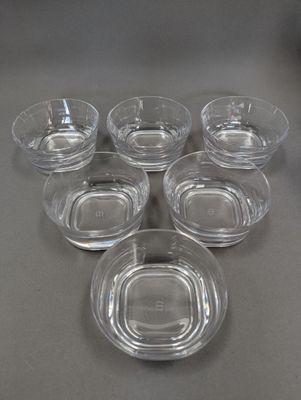 Six bols en verre transparent avec leurs couvercles sont posés sur une table.
