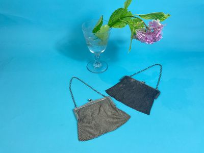 two small purses sitting on top of a table next to a vase of flowers