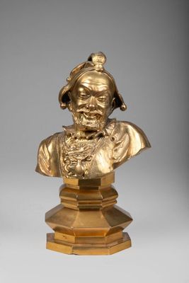 un buste en bronze représentant un homme coiffé d'un chapeau, posé sur un socle