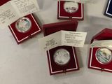 four silver coins in red cases on a white table