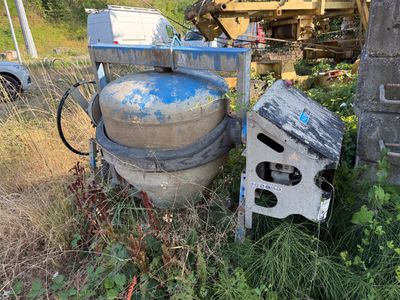un réservoir bleu posé à côté d'un poêle blanc dans l'herbe