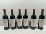 six bottles of wine are lined up on a white surface