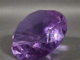 a close up of a purple gemstone on a gray surface