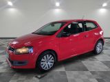 une voiture rouge est garée sur le sol en damier d'un garage