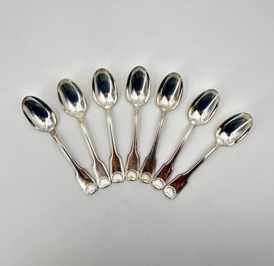 six cuillères en argent sont disposées en ligne sur une surface blanche