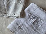 two napkins with embroidered monograms on them on a bed