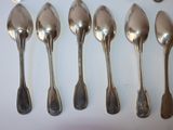six silver spoons are lined up in a row on a white surface